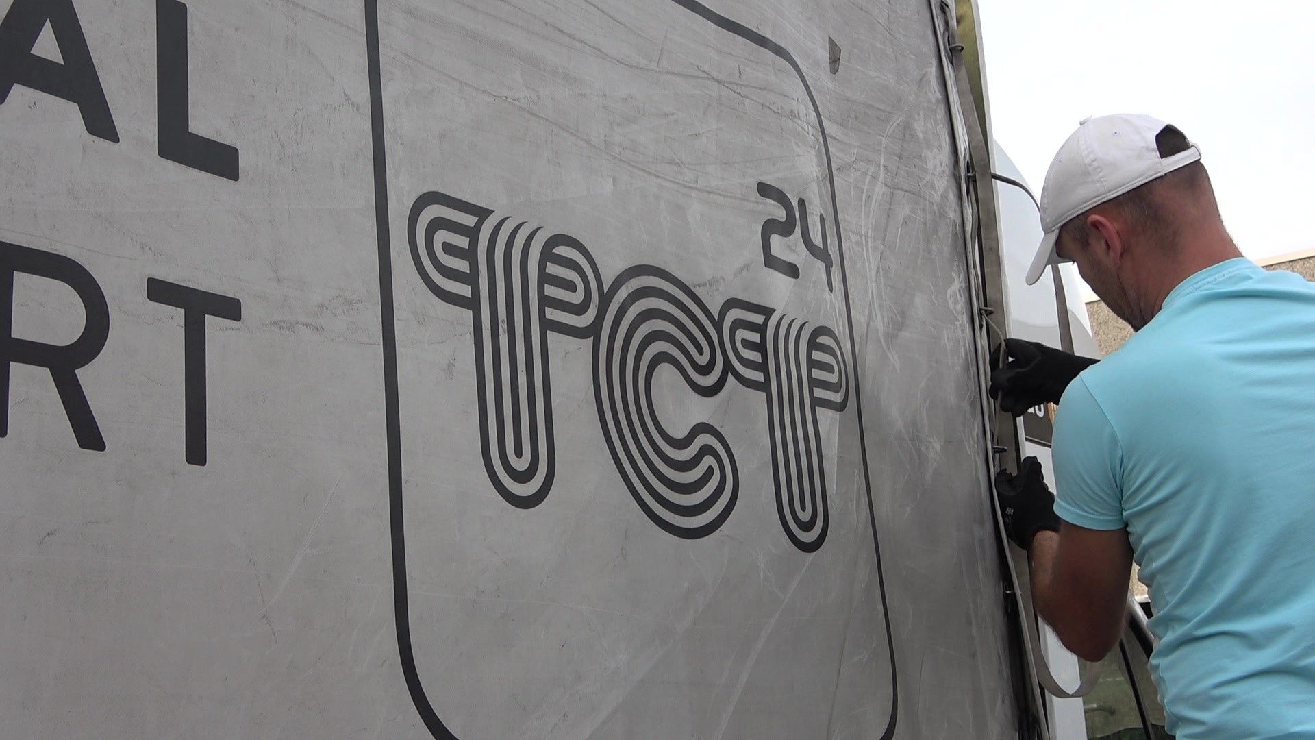 TCT24 driver securing the tarpaulin next to the logo